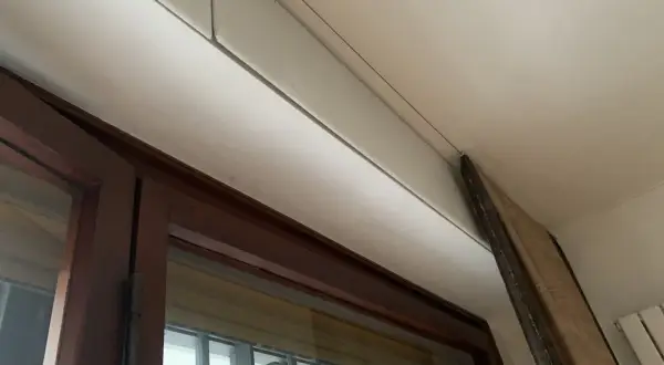 Dettaglio di un cassonetto tapparelle in fase di rimozione, con pannello in legno appoggiato.