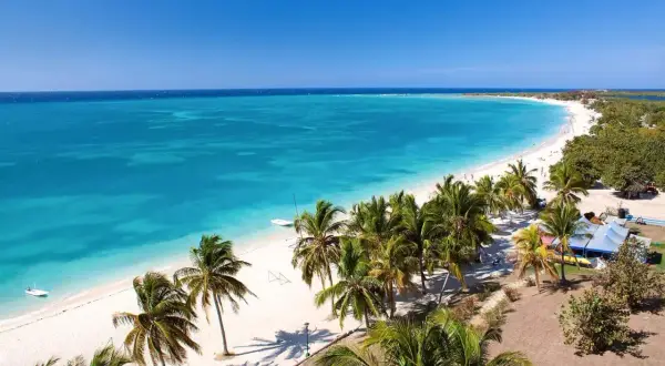 Playa caribeña con palmeras y aguas turquesas, un paraíso antes de la época de huracanes en Cuba.