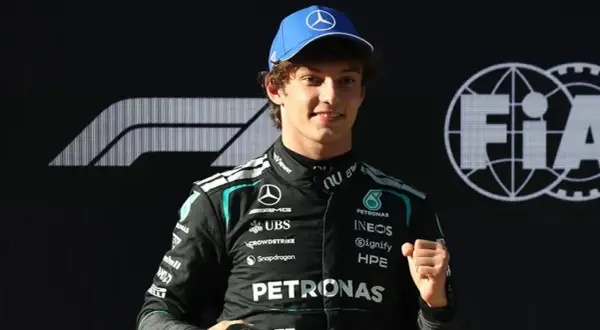 George Russell, piloto de Fórmula 1, celebra con un puño cerrado. Las noticias de Fórmula 1 lo muestran con el logo de Mercedes y FIA.