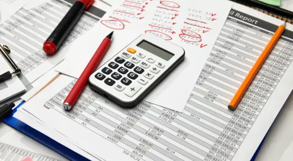Calculatrice, stylos et feuilles de calcul. Préparation des comptes pour la taxe sur les salaires 2024.