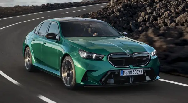 Zielone m5 bmw pędzi po krętej drodze wśród skalistych krajobrazów.