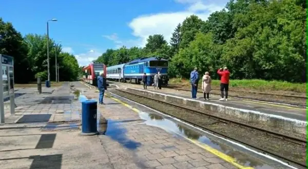 Na peronie czeka pociąg TLK Flisak. Ludzie sprawdzają rozkład jazdy, gotowi do podróży.