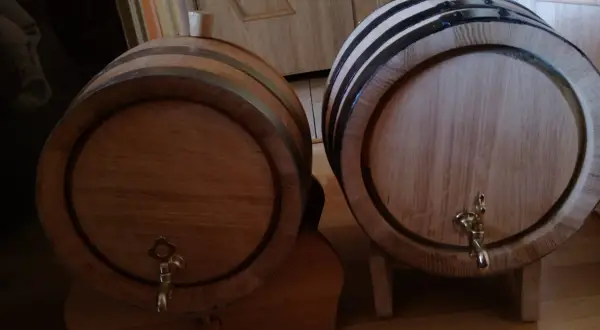 Dwa drewniane beczki, jedna z korkiem, druga z kranikiem, czekają aż coś w nich dojrzewa w dębowych beczkach.