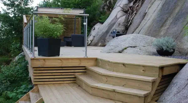 En nybyggd trappa på berg ger tillgång till en altan med sittgrupp och grillplats.