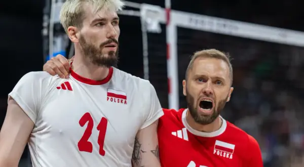 Paweł Zatorski, siatkarz w białej koszulce z numerem 21, otrzymuje wsparcie od kolegi z drużyny w czerwonej koszulce.