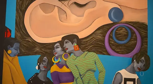 A surreal painting by hispanic artists features women with striking jewelry and bold outfits, set against a backdrop of a giant ear and swirling hair.