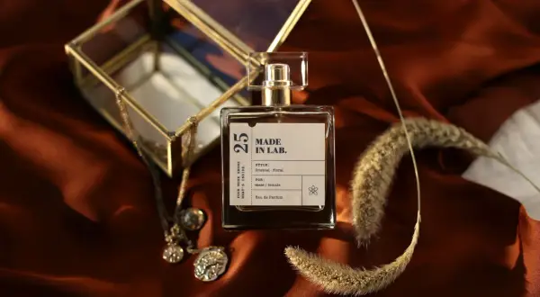 Elegancka butelka perfum "Made in Lab" na satynowym tle. Zastanawiasz się, co dłużej pachnie: woda toaletowa czy perfumowana?