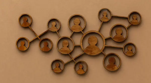 Drewniane figurki ludzi połączone ze sobą, symbolizujące podejście systemowe w psychologii i relacje międzyludzkie.