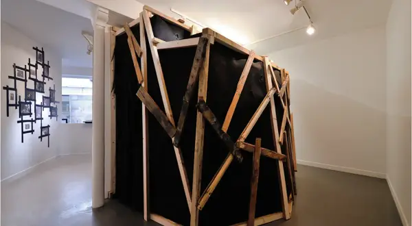 Instalacja artystyczna z czarnym materiałem i drewnianą konstrukcją, nawiązująca do prac Miroslava Tichego.