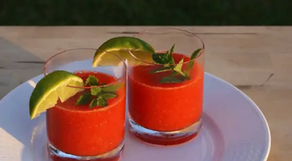 Två glas med en uppfriskande strawberry daiquiri, garnerade med lime och mynta. Perfekt för en solig sommardag.