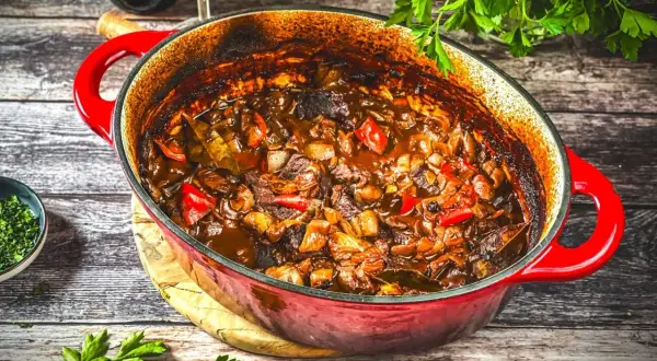 Herzhaftes Schweinegulasch im roten Bräter, bereit zum Servieren. Ein köstliches Schweinegulasch Rezept für gemütliche Abende.