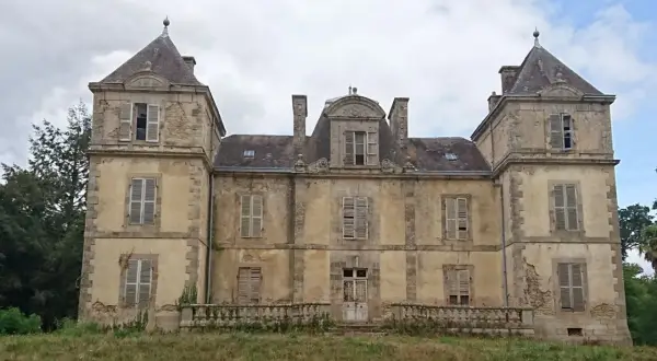 Vaste manoir abandonné en Bretagne, aux façades décrépites et aux volets clos, témoignant d'une histoire oubliée.