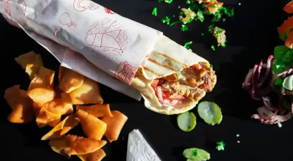 Pyszny kebab w tortilli z chrupiącymi chipsami i świeżymi dodatkami, gotowy do zjedzenia.