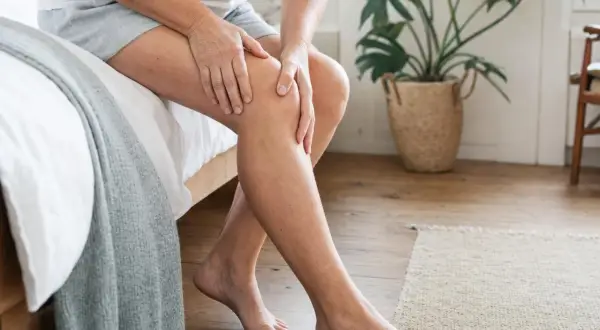 Donna si tocca il ginocchio, forse per un problema al liquido sinoviale.
