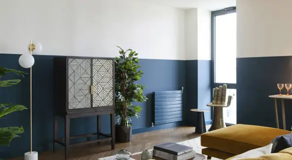 Soggiorno moderno con pareti bicolore blu e bianche, un mobile etnico e un divano giallo ocra. Idee pareti colorate particolari per un look audace.