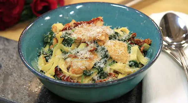 En härlig kycklingpasta med soltorkade tomater och spenat, perfekt för ett snabbt och gott kycklingpasta recept. Serveras i en vacker blå skål.