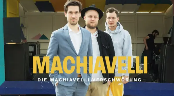 Drei Männer stehen vor einer Bühne, auf der "MACHIAVELLI" steht. Sie sind die Macher des Machiavelli Podcast.