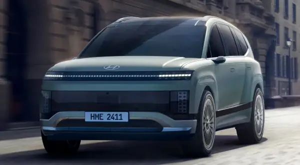 Przyszłościowy Hyundai Ioniq 9 w kolorze miętowym przemierza miejskie ulice, prezentując swój unikalny design i innowacyjne oświetlenie.