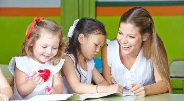 Lehrerin hilft Kindern beim Malen. Ein schönes lerngeschichte beispiel, wie Kinder kreativ werden.