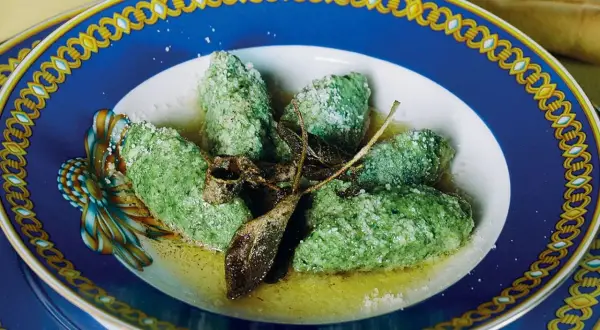 Strangolapreti alla trentina, verdi e saporiti, serviti in un piatto elegante con burro fuso e salvia croccante.