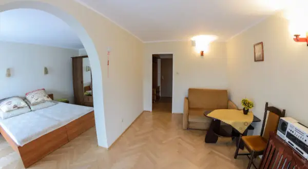 Pokój w sanatorium uzdrowiskowym Limba: łóżko, kanapa, stolik z kwiatami i radio.
