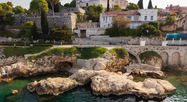Felsige Küste mit kristallklarem Wasser und einer Kirche auf dem Hügel. Entdecke Rovinj Geheimtipps abseits der Touristenpfade.