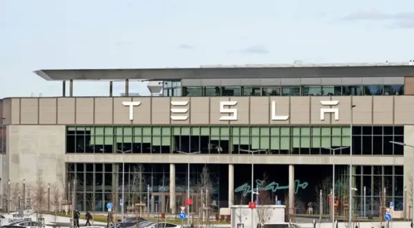 Tesla-Fabrik mit vielen Autos auf dem Parkplatz. Der Tesla-Betriebsrat vertritt die Interessen der Belegschaft.