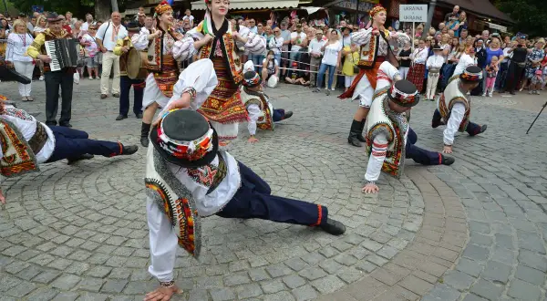 Tancerze w barwnych strojach ludowych wykonują akrobacje podczas międzynarodowego festiwalu folkloru ziem górskich.