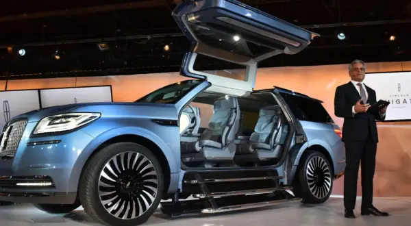 Niebieski Lincoln Navigator Concept z otwieranymi drzwiami typu gullwing i wysuwanymi stopniami. Prezentacja futurystycznego samochodu.