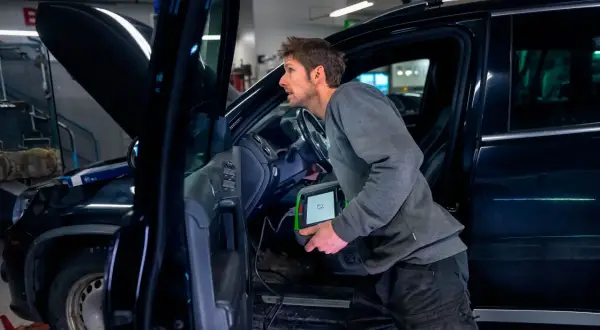Mekaniker använder diagnosverktyg för att kontrollera bilens elektriska handbroms.