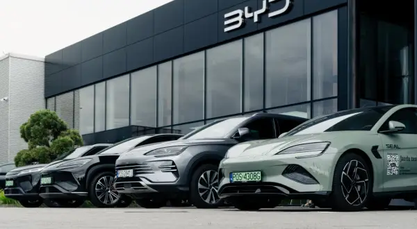 Rząd nowoczesnych samochodów BYD zaparkowany przed salonem. Wśród nich zielony model z napisem "Jazda testowa".