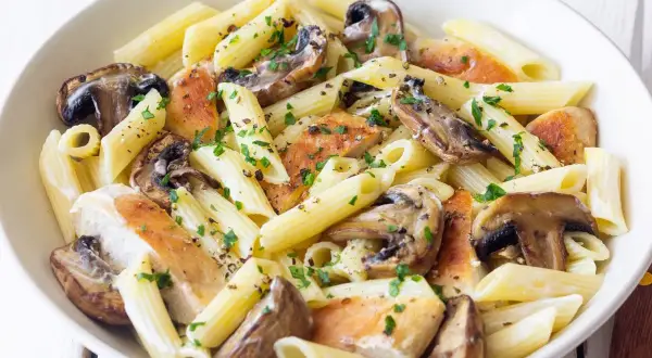 Penne z kurczakiem i pieczarkami, posypane natką pietruszki i pieprzem. Pyszne danie, które z pewnością zadowoli każdego miłośnika makaronu z kurczakiem.