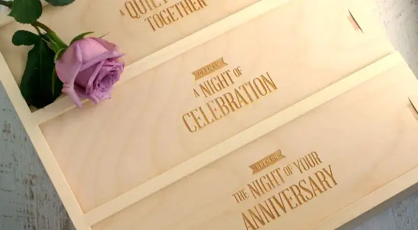 Drewniane pudełko na wino z grawerem "A Quiet Night Together", "A Night of Celebration", "The Night of Your Anniversary" i różową różą.