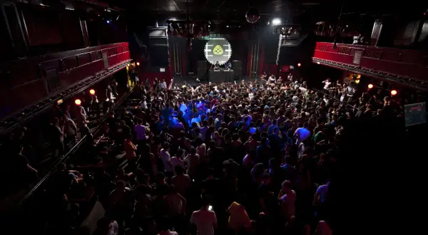 Folla in delirio al Nitsa Club, luci soffuse e musica pulsante.