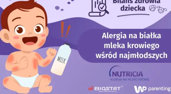Uśmiechnięte dziecko z zaczerwienioną skórą obok butelki z mlekiem. Temat: po jakim czasie pojawia się alergia na mleko modyfikowane.
