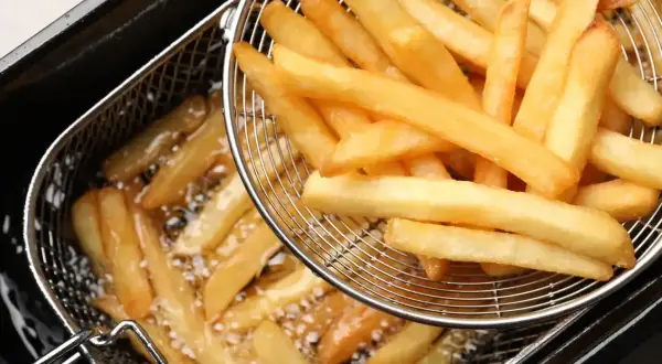 Złociste, chrupiące frytki mcdonald w koszyku do smażenia.