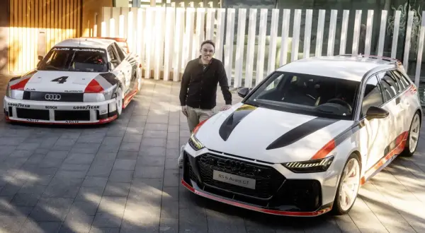 Mężczyzna stoi obok Audi RS6 Avant GT, z legendarnym Audi Quattro z lat 80. w tle.