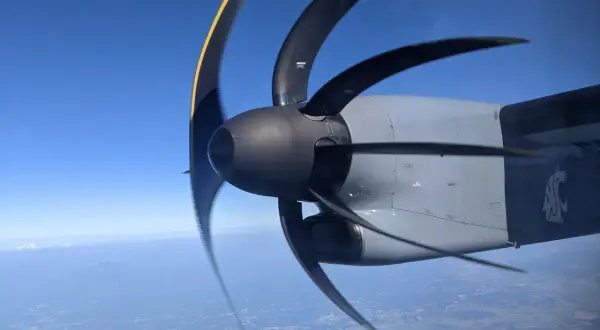 Wirujący śmigłowiec samolotu z efektem rolling shutter nad miastem i górami w oddali.