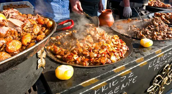 Varm mat ångar från stora pannor på en marknad i Budapest. Kött och grönsaker tillagas.