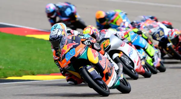 Pilotos de Moto3 compiten en una carrera, mostrando la potencia y velocidad de estas motos. El número 99 destaca en primer plano.