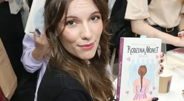 Kobieta trzyma książkę "Rodzina Monet - Skarb" z wizerunkiem dziewczyny z warkoczem.