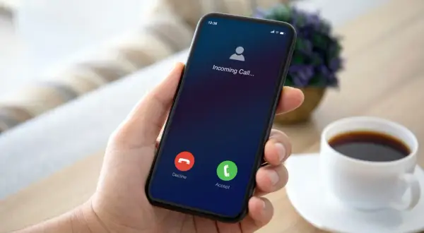 Dłoń trzyma smartfon Samsung z ekranem przychodzącego połączenia. Możliwe przekierowanie połączeń.