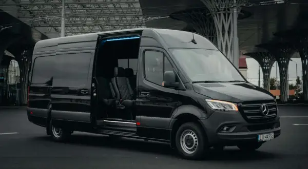 Czarny Mercedes Sprinter z otwartymi drzwiami i niebieskim podświetleniem. Zastanawiasz się, ile kosztuje bus do Holandii?
