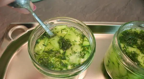 Ein Glas Gurkensalat mit Dill wird mit einem Löffel vorbereitet, bereit zum Gurkensalat einkochen.