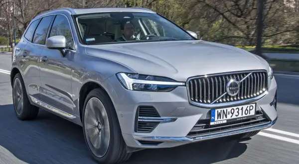 Srebrny Volvo XC60 2026 jedzie po drodze, za kierownicą mężczyzna.
