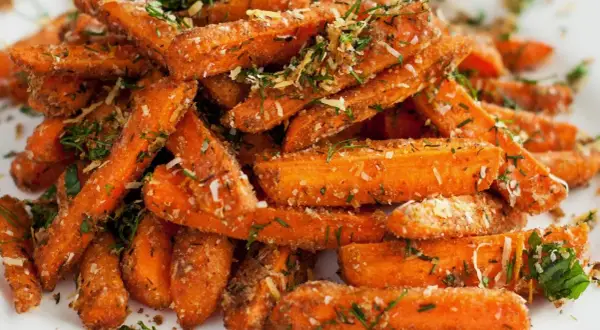 Chrupiące frytki z marchewki, posypane ziołami i parmezanem, wyglądają apetycznie.