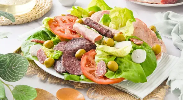 Amanida catalana con lechuga, tomate, aceitunas, cebolla y embutidos variados.