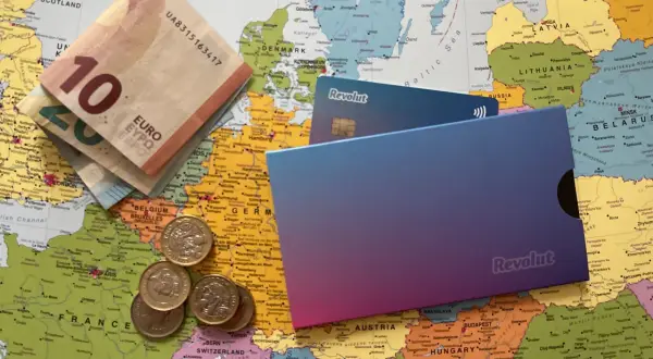Euro banknoty, monety i karty Revolut leżą na mapie Europy. Czy Revolut jest darmowy? Sprawdź, zanim wyruszysz w podróż!