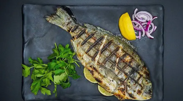 Grillowana ryba z cytryną, cebulą i natką pietruszki. Idealne jakie przyprawy do ryby na obiad.