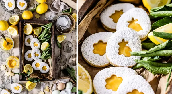 Zuckrige Kekse mit leuchtend gelbem Lemon Curd gefüllt, umgeben von frischen Zitronen und grünen Blättern.